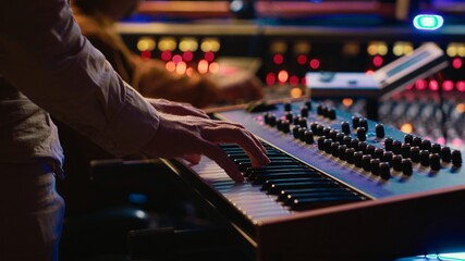 Skilled artist playing piano electronic keyboard in control room, recording new tracks with midi...