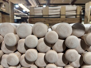 Wooden baseball bats stacked in storage at a manufacturing facility during daylight hours