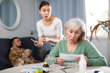 Obraz premium Young wife and an elderly mother discuss what medicines are needed for a sick husband
