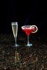 Margarita made of blood orange and a tall glass of champagne on a black background