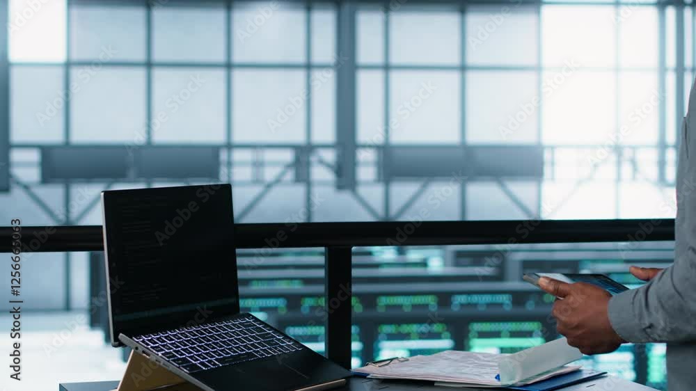 Poster technician in data center with laptop and tablet integrating ai driven automation tools. server room