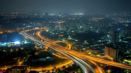 Obraz premium Night cityscape with illuminated highway interchange and buildings.