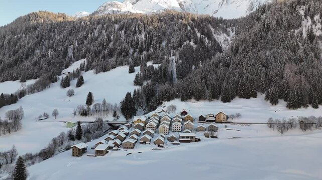 Aerial video above a small snowy village in winter in the Fontana val Bedretto Snow area