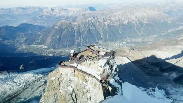 Breathtaking view from the highest point of Aiguille du Midi with the glass skywalk, overlooking the lower cable car station, Chamonix valley, and the stunning peaks of the French Alps.