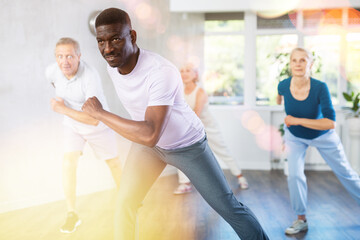 Obraz premium Energetic African American man practicing hip-hop movements during adult group dance class in studio