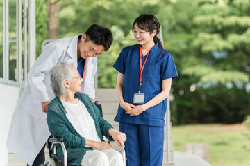 病院・介護施設にいる車椅子に乗った高齢者と医師・看護師
