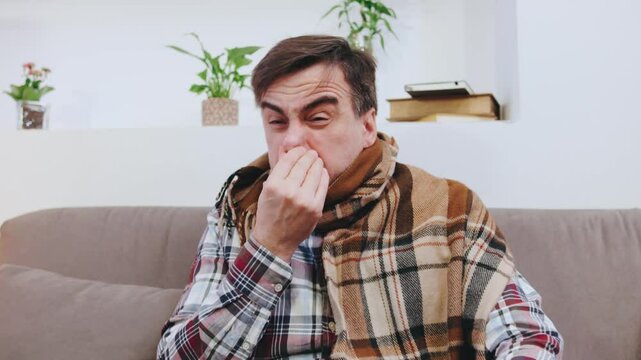 An elderly man, wrapped in a cozy blanket sneezing, coughing and fighting off a cold in a bright living room filled with plants and cozy decor.