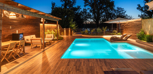 Luxurious outdoor pool area with cozy wooden deck and ambient lighting