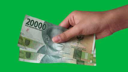 Indonesian rupiah currency, 20,000 rupiah, is held by women's hands. Green screen background