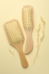 Wooden hair brushes and spikes on beige background, flat lay