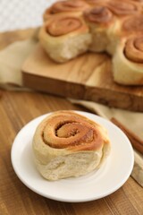 Freshly baked cinnamon roll on wooden table, closeup