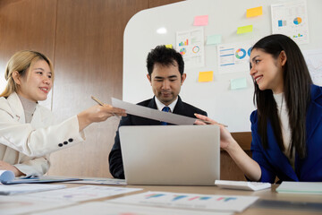 Team members exchanging documents in a meeting, highlighting cooperation and teamwork in the...
