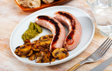 Roasted sausages served with side dish of fried mushrooms and basil pesto sauce