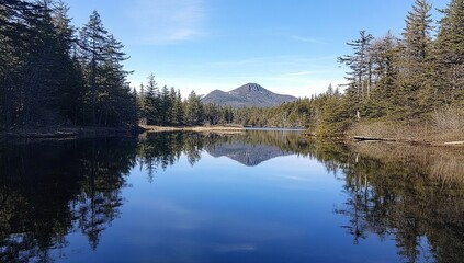 Fototapeta premium Serene Lake Reflects Majestic Mountain Peak on a Sunny Day, Tranquil Nature Scene with Crystal Clear Waters.
