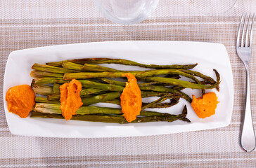 Charred asparagus served with classic Romesco sauce, featuring smoky red peppers and almonds,...