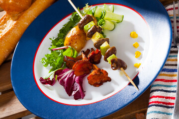 Appetizing chicken heart brochettes with fresh avocado served with fried chanterelles and vegetable garnish