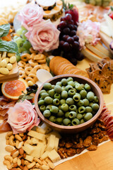 Gourmet platter featuring olives, cheese, fruits, and nuts arranged beautifully for a gathering