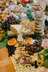 Impressive spread of cheeses, fruits, and snacks arranged on a wooden table for a gathering