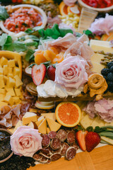 Colorful charcuterie board featuring various cheeses, fruits, and flowers at a spring gathering