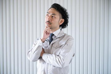 A man in work clothes in front of a factory, distressed.