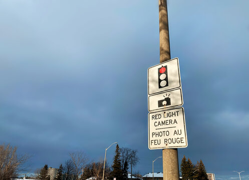 Red Light Camera Traffic Sign with Bilingual Text on a Street Pole