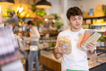 Guy pick up pasta in store. Customer consider make choice noodles, compare varieties products....
