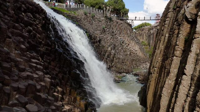 People cross the canyon on a suspension bridge in the basalt prisms of Huasca de Ocampo, Mexico. Still shot near the waterfalls between the rock walls