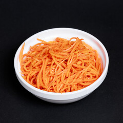 Korean-style spicy carrot salad on a white plate on a dark background