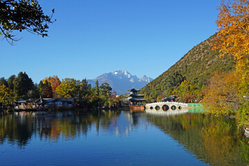 Fototapeta premium Black dragon pool in Lijiang Ancient Town with best views of Jade Dragon Snow Mountain. Famous travelling destination in Yunnan province, China