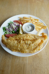 Crispy fried fish served with salad and fries on a plate