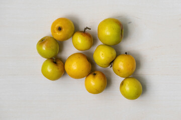 Fresh ripe plum fruits on a light wooden surface. Locally called Boroi or Kul in Bangladesh, this fruit is also known as Indian jujube, Chinese date, or Chinee apple. Top view.