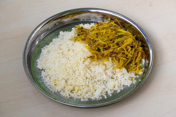 Plain white rice and thinly sliced potato fry (aloo bhaji) served on a steel plate with a wooden backdrop. Rice is a staple food in Bangladesh, rich in nutrients like fiber and vitamins.