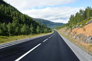       There is a long highway with a car on it that is winding