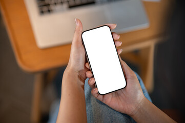 A close-up top view of a woman using a smartphone while sitting indoors.