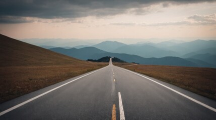  A tranquil highway stretches toward distant mountains under a moody sky
