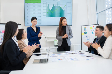 A group of excited, happy team members or employees and their computers are applauding in...