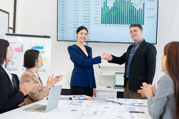 A group of excited, happy team members or employees and their computers are applauding in...