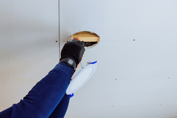 Contractor works on repairing ceiling led light by fixing cut out section with renovation skills.