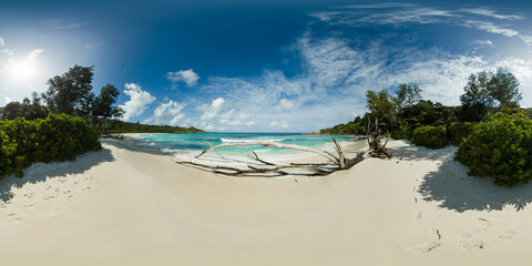 Golden sands beach meet turquoise waters under a clear sky, bordered by lush greenery. Anse Cocos...