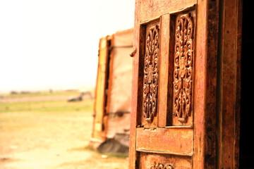 This image showcases a beautifully crafted traditional Mongolian wooden door, adorned with intricate ancient patterns, standing wide open. The door is a masterpiece of Mongolian craftsmanship