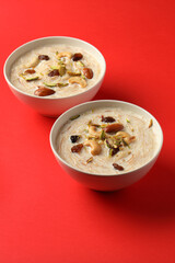 Kheer traditional Indian dessert served in ceramic bowl on red background 