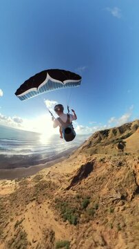 Paraglider soaring in New Zealand coast at sunset, adventure concept.