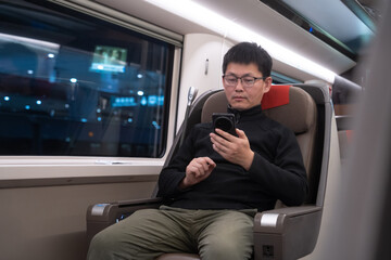 asian man is using smart phone on a train