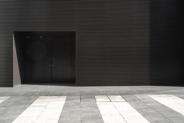 Modern building facade with large door and striped pavemen