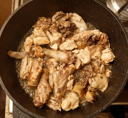 A pan of meat is cooking on a stove