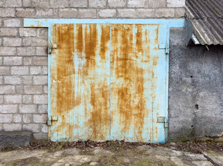 A rusted blue door with a brick wall behind it