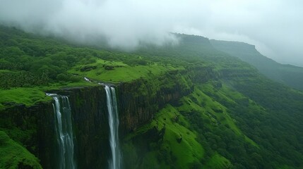 Fototapeta premium A high-angle view of a cascading waterfall cutting through a lush green valley