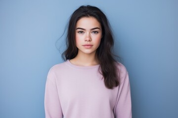 Fototapeta premium A woman with long hair is wearing a pink sweater and is looking at the camera
