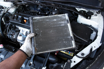 Mechanic holding radiator or evaporator of car air conditioner during car maintenance , oil gear...