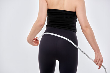 An Asian woman is on a diet and measuring her waist size using a tape measure.	
